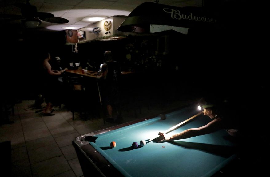 Lisa Borruso plays pool using a headlamp as the power remains out following Hurricane Irma at Gators' Crossroads in Naples, Fla., Monday, Sept. 11, 2017. Statewide, an estimated 13 million people, or two-thirds of Florida's population, remained without power. That's more than the population of New York and Los Angeles combined. Officials warned it could take weeks for electricity to be restored to everyone. (AP Photo/David Goldman)