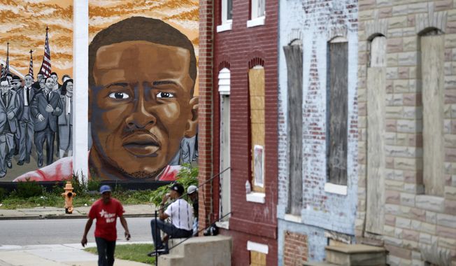 A mural depicting Freddie Gray is seen past blighted row homes in Baltimore, at the intersection where Gray was arrested. The U.S. Department of Justice won&#x27;t bring federal charges against six police officers involved in the arrest and death of Freddie Gray, a young black man whose death touched off weeks of protests and unrest in Baltimore. The officers were charged by state prosecutors after Gray&#x27;s neck was broken in the back of a police transport wagon in April of 2015. (AP Photo/Patrick Semansky File)