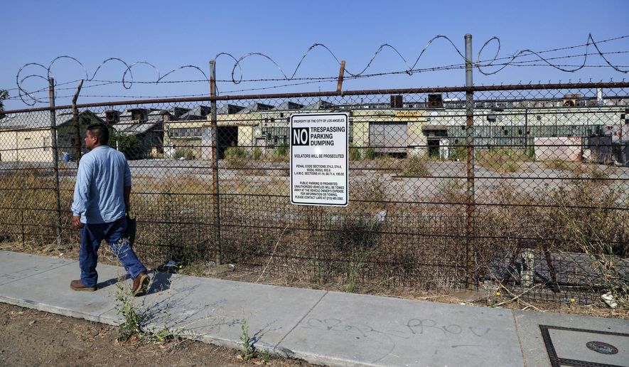 FILE--This July 29, 2016, file photo shows a pedestrian walking past the outside of an old derelict factory where the Slauson-Wall Park is meant to be built in Los Angeles. Lawmakers want to spend $700 million to build new parks as part of a $4 billion bond proposal, but many parks promised under the last bond in 2006 still aren't finished. (AP Photo/Nick Ut, file)