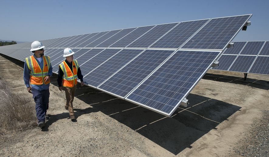 In this Thursday, Aug. 17, 2017, file photo, solar tech Joshua Valdez, left, and senior plant manager Tim Wisdom walk past solar panels at a Pacific Gas and Electric Solar Plant, in Dixon, Calif. Higher energy costs led to prices at the wholesale level rising in August 2017 at the fastest pace in four months, according to information released Wednesday, Sept. 13, 2017, by the Labor Department. (AP Photo/Rich Pedroncelli, File)
