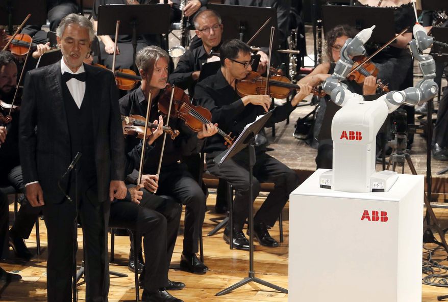 Italian tenor Andrea Bocelli, left, performs Giuseppe Verdi's opera "La Donna e' Mobile", on stage next to the robot YuMi conducting the Lucca Philharmonic Orchestra, at the Verdi Theater, in Pisa, Italy, Tuesday, Sept. 12, 2017. A world famous tenor, a celebrated orchestra and a robot conductor were the highlight of Pisa's inaugural International Robotics Festival which runs from Sept. 7 to Sept. 13. (International Robotics Festival Pisa via AP)