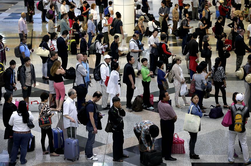 Travelers line up at the immigration counters as they make their way through the departure hall at the Kuala Lumpur International Airport. (Associated Press)