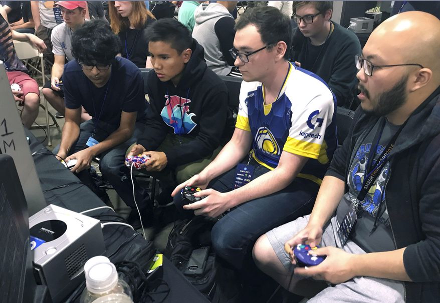 In this Aug. 25, 2017, photo, Connor Nguyen, at right, and Griffin Williams, second from right, compete in a "Super Smash Bros. Melee" tournament at the Shine eSports festival at the Seaport World Trade Center in Boston. Griffin, 21, is captain of an esports team at the University of California, Irvine, and Nguyen, 23, is a graduate of the school. The University of California, Irvine, is among a growing number of U.S. schools starting to offer at least partial scholarships to students who compete in esports, competitive video-game playing. (AP Photo/Collin Binkley)