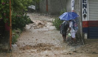 People walk under a downpour on a flooded street in Acapulco, Guerrero state, Mexico, Thursday, Sept. 14, 2017. Hurricane Max hit Mexico&#39;s southern Pacific coast as a Category 1 storm Thursday and was expected to move inland into Guerrero state, a region that includes the resort city of Acapulco.(AP Photo/Bernandino Hernandez)
