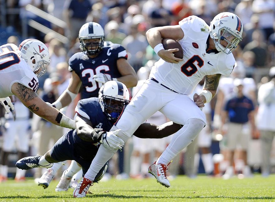 FILE - In this Sept. 17, 2016, file photo, Connecticut's Junior Joseph, left, tackles Virginia quarterback Kurt Benkert (6) during the first half of an NCAA college football game at Pratt & Whitney Stadium at Rentschler Field in East Hartford, Conn. The two teams meet on Saturday. (AP Photo/Jessica Hill, File)