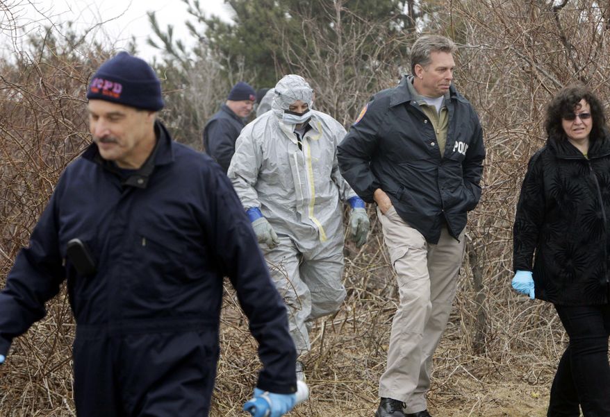 FILE - In this April 11, 2011, file photo, emergency personnel search through the brush for human remains near Jones Beach in Wantagh, N.Y. On Tuesday, Sept. 12, 2017, Suffolk County Assistant District Attorney Robert Biancavilla said after the sentencing of Long Island carpenter John Bittrolff for killing two prostitutes in the early 1990s, that Bittrolff may be responsible for killing at least one of 10 victims whose remains have been found along a Long Island beach highway. (AP Photo/Seth Wenig, File)