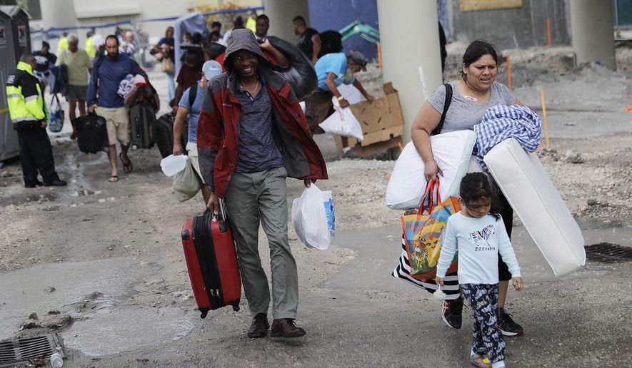FILE - In this Sept. 9, 2017 file photo, evacuees are moved to another building with more bathrooms while sheltering at Florida International University ahead of Hurricane Irma in Miami. Students in two of the nation’s largest school districts still don’t know when they’ll return to class, forcing many Florida parents to juggle childcare as they head into a second week of recovering from Hurricane Irma. Miami-Dade and Broward counties had hoped to resume operations Monday, Sept. 18.. But dozens of schools in the two districts , which serve almost 700,000 students, are still without power. (AP Photo/David Goldman)