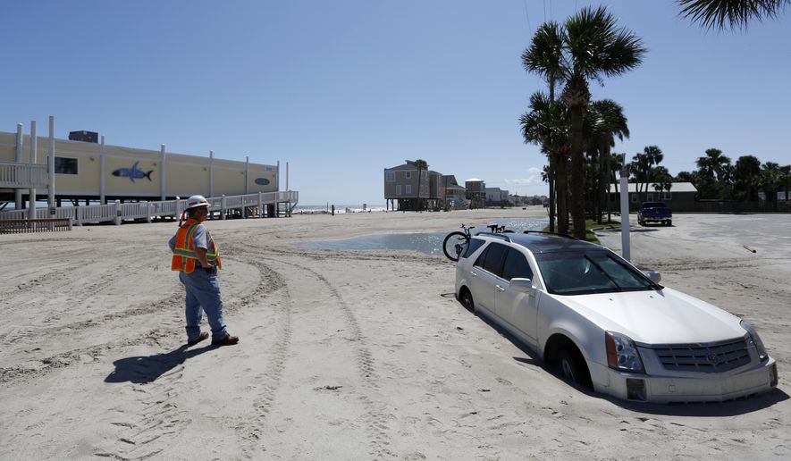 Greg Smith with the South Carolina Department of Transportation waits to remove a car stuck in Palmetto Blvd., in Edisto Beach, S.C., Tuesday, Sept. 12, 2017, as the road is covered in several feet of sand after Tropical Storm Irma hit. Edisto Beach suffered the same fate last year with Hurricane Matthew. (AP Photo/Mic Smith)