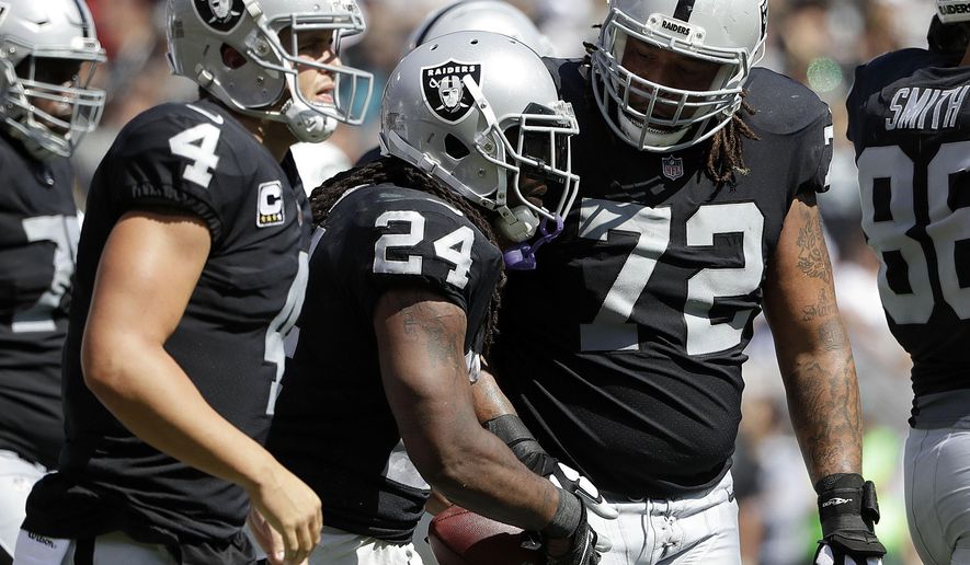 Oakland Raiders running back Marshawn Lynch (24) is congratulated by quarterback Derek Carr (4) and tackle Donald Penn (72) after scoring a touchdown against the New York Jets during the first half of an NFL football game in Oakland, Calif., Sunday, Sept. 17, 2017. (AP Photo/Marcio Jose Sanchez)