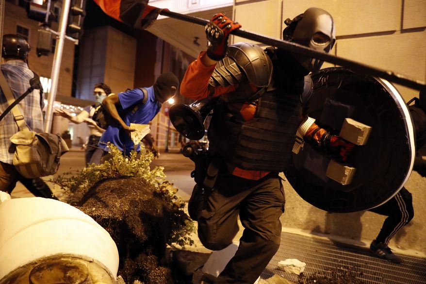 People run after vandalizing as demonstrators march in response to a not guilty verdict in the trial of former St. Louis police officer Jason Stockley, Sunday, Sept. 17, 2017, in St. Louis. Stockley was acquitted in the 2011 killing of a black man following a high-speed chase. (AP Photo/Jeff Roberson)