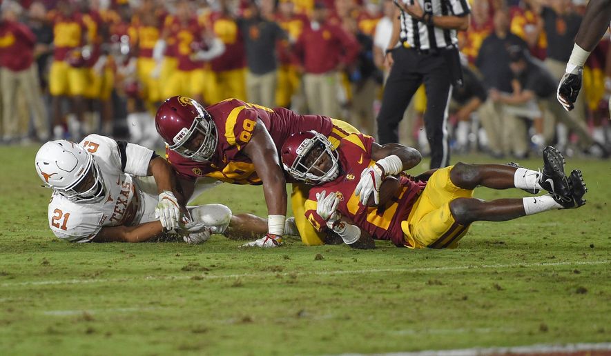 Southern California cornerback Ajene Harris, right, recovers a fumble by Texas as Texas running back Kyle Porter, left, and defensive lineman Christian Rector fall during the second overtime of an NCAA college football game, Saturday, Sept. 16, 2017, in Los Angeles. USC won 27-24 in two overtimes. (AP Photo/Mark J. Terrill)