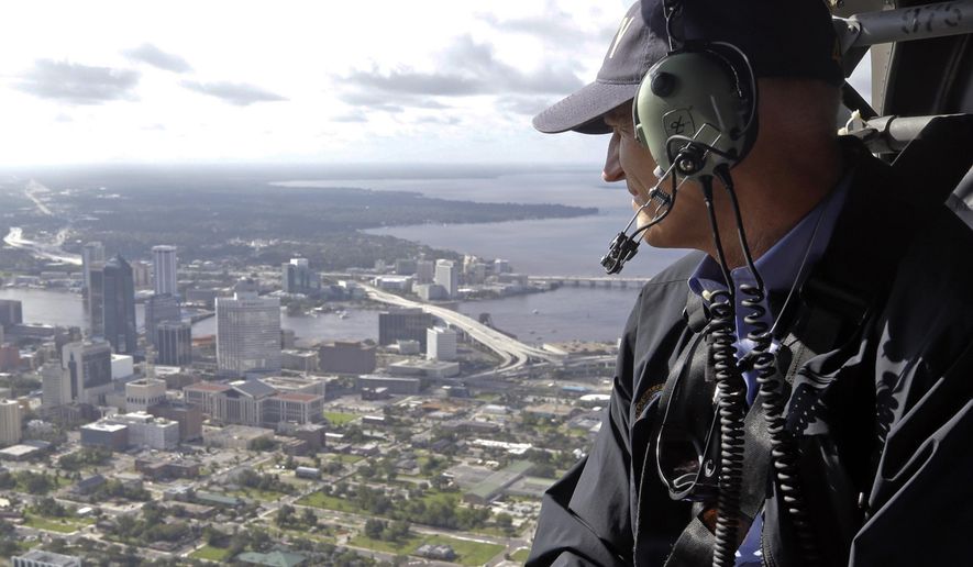 FILE - In this Sept. 12, 2017, file photo, Gov. Rick Scott assesses flooding damage over Jacksonville, Fla., in the aftermath of Hurricane Irma. The combined tab from Hurricanes Harvey and Irma is expected to hit $200 billion or more. While the federal government is expected to pay most of that, the affected state and local governments have to start paying for recovery now and eventually could be on the hook for tens of millions of dollars or more. (AP Photo/John Raoux, File)