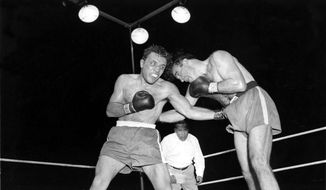 FILE - In this June 16, 1949, file photo, Jake LaMotta, left, pounds Marcel Cerdan in third round of a world middleweight title bout in Detroit, Mich. LaMotta won the title by a knockout in the tenth round. LaMotta, whose life was depicted in the film “Raging Bull,” died Tuesday, Sept. 19, 2017, at a Miami-area hospital from complications of pneumonia. He was 95. (AP Photo/File)