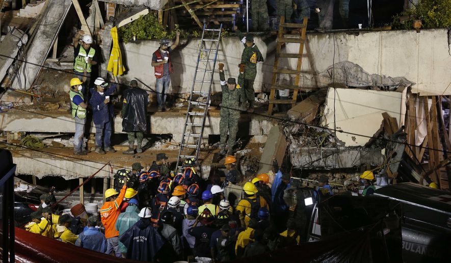 Rescue personnel work on the rescue of a trapped child at the collapsed Enrique Rebsamen primary schoool in Mexico City, Sept. 20, 2017.  A wing of the school collapsed after a powerful earthquake jolted central Mexico on Tuesday, killing scores of children and trapping others. (AP Photo/Marco Ugarte)