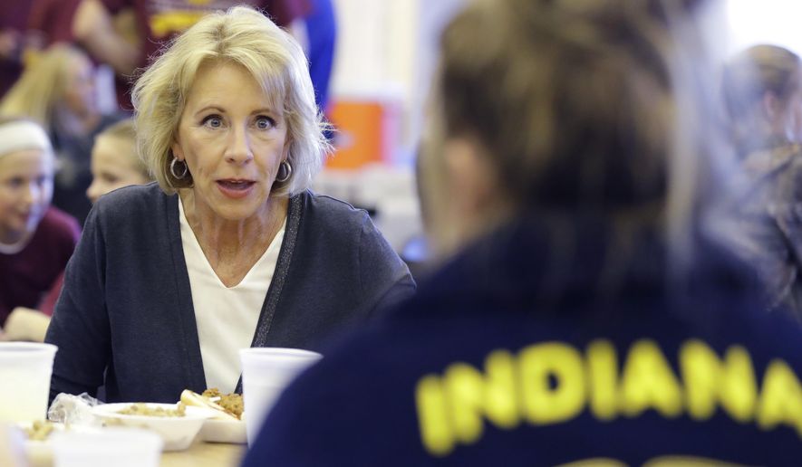 In this Sept. 15, 2017 photo, U.S. Secretary of Education Betsy DeVos talks with Gracie Johnson during a hog roast before a high school football game between Eastern Hancock and Knightstown in Charlottesville, Ind. DeVos uses a private jet to fly around the country to tour schools and attend other work events, the Associated Press has learned.  (AP Photo/Darron Cummings)