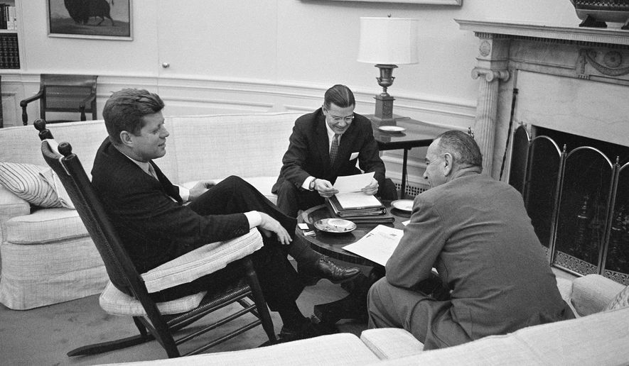FILE - In this March 16, 1961 file photo, President John F. Kennedy sits in his favorite rocking chair in his office during a meeting with Secretary of Defense Robert McNamara and Vice President Lyndon B. Johnson, right, at the White House in Washington. A replica of the rocking chair commissioned and gifted by Kennedy is up for sale at a Los Angeles auction that will take place on Nov. 17, 2017. (AP Photo/Henry Burroughs, File)