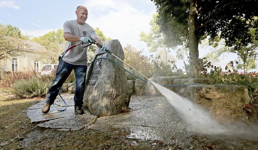 Cal Steinberg of the City of Madison, Wis. Facilities and Maintenance Department cleans the area around a memorial at the Gates of Heaven Synagogue building after using a high pressure hose and 248-degree water to remove anti-Semitic graffiti from the stone marker outside the historic building in the city Wednesday, Sept. 20, 2017. (John Hart/Wisconsin State Journal via AP)