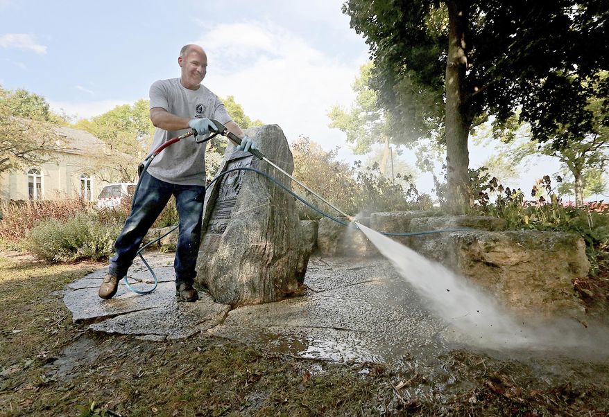 Cal Steinberg of the City of Madison, Wis. Facilities and Maintenance Department cleans the area around a memorial at the Gates of Heaven Synagogue building after using a high pressure hose and 248-degree water to remove anti-Semitic graffiti from the stone marker outside the historic building in the city Wednesday, Sept. 20, 2017. (John Hart/Wisconsin State Journal via AP)