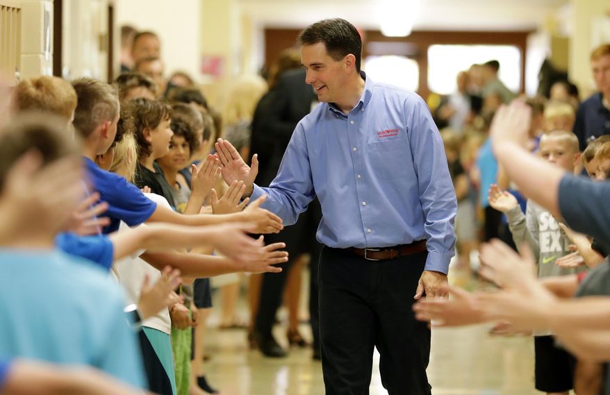 Governor Scott Walker high-fives students after signing the 2017-2019 state budget bill into law Thursday,  Sept. 21, 2017, at Tullar Elementary School in Neenah, Wis. (Dan Powers/The Post-Crescent via AP)