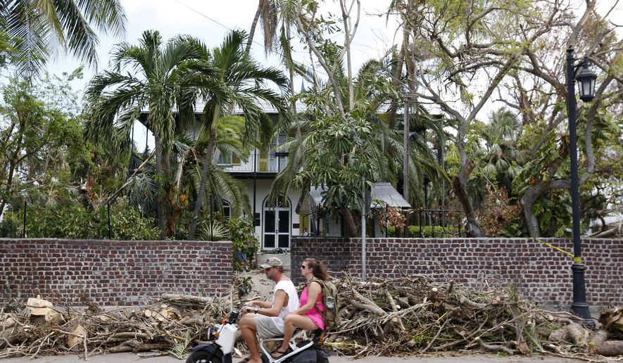 A couple rides past the entrance to the Ernest Hemingway Home &amp; Museum, Thursday, Sept. 21, 2017, in Key West, Fla. Businesses and residents in the Keys are removing debris and fixing damage caused by Hurricane Irma in anticipation for the return of tourists in the area. (AP Photo/Wilfredo Lee)