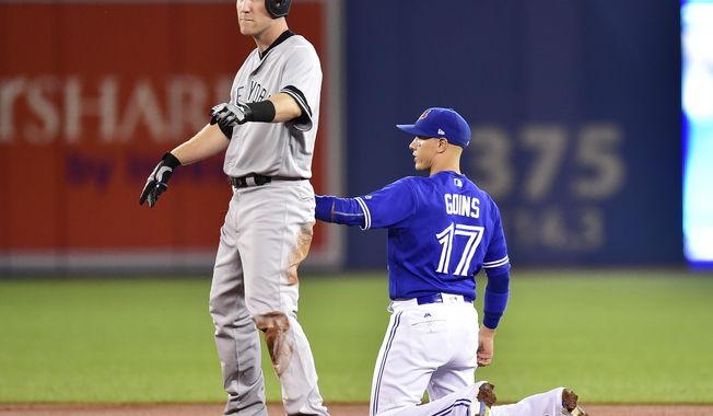 Toronto Blue Jays shortstop Ryan Goins (17) holds the tag on New York Yankees third baseman Todd Frazier (29) after hitting a double during the third inning of a baseball game, Friday, Sept. 22, 2017 in Toronto.  Blue Jays shortstop Ryan Goins used the hidden-ball trick to retire New York Yankees slugger Todd Frazier on Friday night. (Frank Gunn/The Canadian Press via AP)