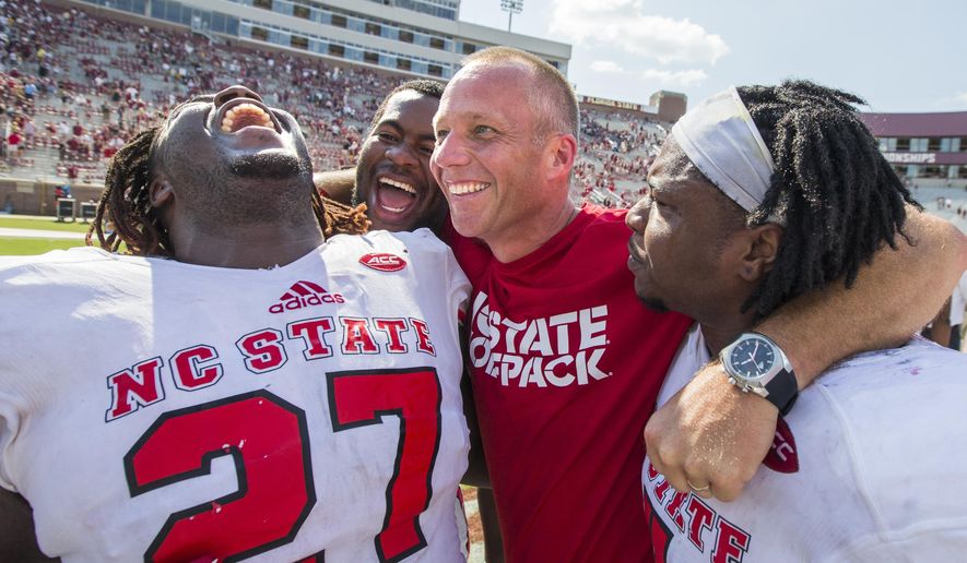 North Carolina State players, from left, Dakwa Nichols (27), defensive tackle B.J. Hill, head coach Dave Doeren and linebacker Jerod Fernandez celebrate defeating Florida State 27-21 in an NCAA college football game in Tallahassee, Fla., Saturday, Sept. 23, 2017. (AP Photo/Mark Wallheiser)