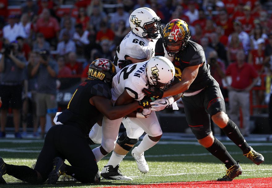 Central Florida running back Taj McGowan, center, rushes for a touchdown past Maryland linebackers Jermaine Carter Jr., left, and Shane Cockerille, right, in the first half of an NCAA college football game in College Park, Md., Saturday, Sept. 23, 2017. Also pictured is Central Florida offensive lineman Aaron Evans (66). (AP Photo/Patrick Semansky)