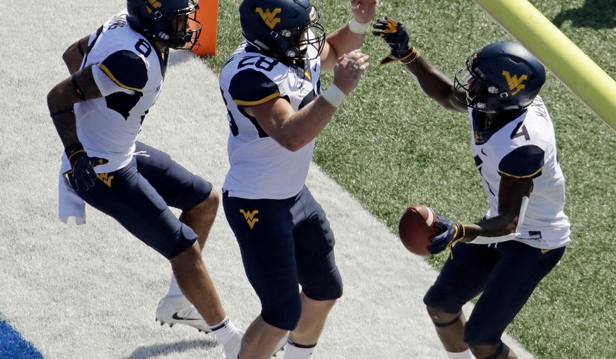 West Virginia running back Kennedy McKoy (4) celebrates with tight end Elijah Wellman (28) and wide receiver Marcus Simms (8) after scoring a touchdown during the first half of an NCAA college football game against Kansas Saturday, Sept. 23, 2017, in Lawrence, Kan. (AP Photo/Charlie Riedel)