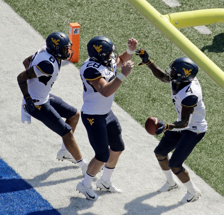 West Virginia running back Kennedy McKoy (4) celebrates with tight end Elijah Wellman (28) and wide receiver Marcus Simms (8) after scoring a touchdown during the first half of an NCAA college football game against Kansas Saturday, Sept. 23, 2017, in Lawrence, Kan. (AP Photo/Charlie Riedel)