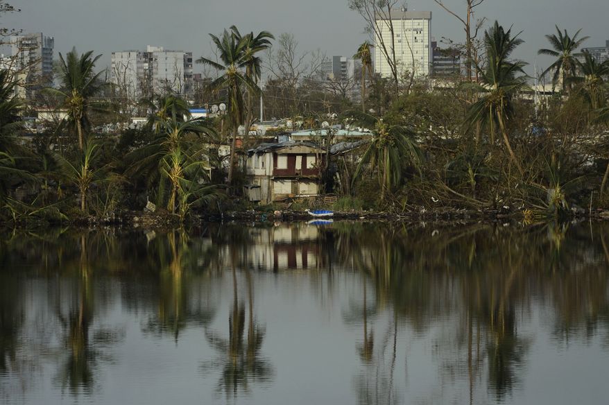 Trees are reflected in the water in the Buena Vista community in the aftermath of Hurricane Maria in San Juan, Puerto Rico, Sunday, Sept. 24, 2017. (AP Photo/Carlos Giusti)