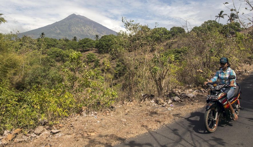 A villager rides past by with Mount Agung seen in the background in Karangasem, Bali, Indonesia, Sunday, Sept. 24, 2017. Thousands of villagers on the Indonesian resort island have been evacuated to temporary shelters amid fear that Mount Agung will erupt for the first time in more than half a century. Its last eruption in 1963 killed 1,100 people. (AP Photo/J.P. Christo)
