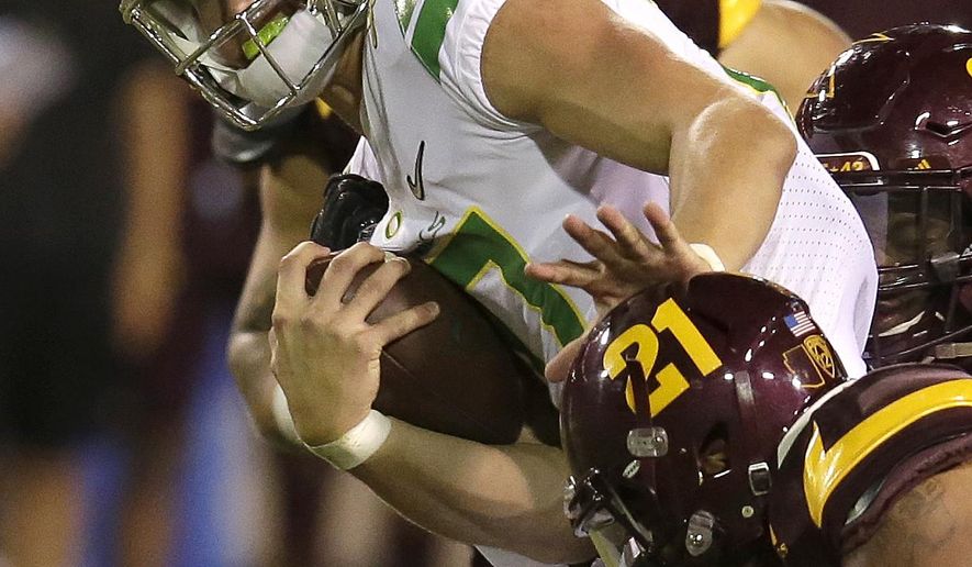 Oregon quarterback Justin Herbert (10) pushes off from Arizona State defensive back Chad Adams during the second half of an NCAA college football game, Saturday, Sept. 23, 2017, in Tempe, Ariz. (AP Photo/Rick Scuteri)