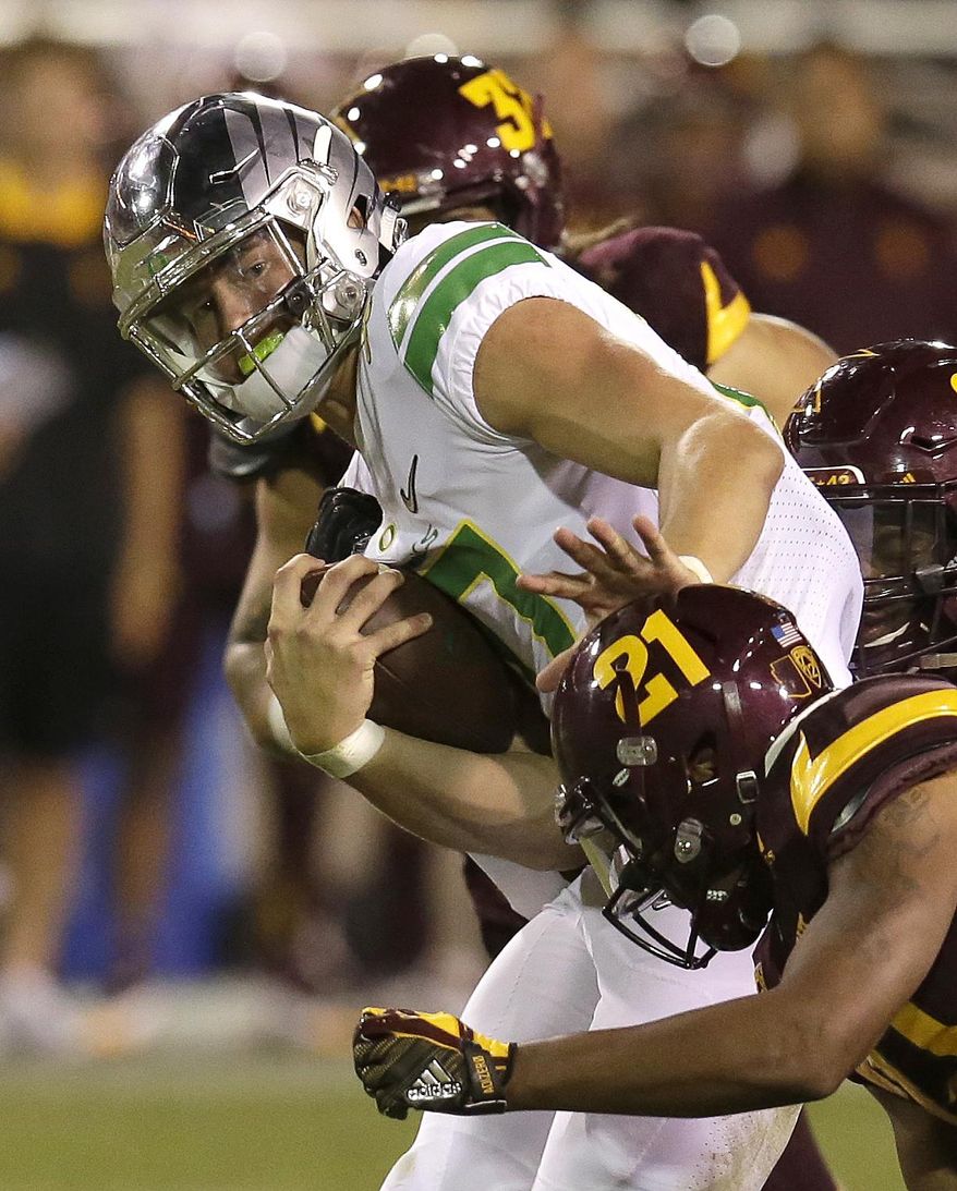 Oregon quarterback Justin Herbert (10) pushes off from Arizona State defensive back Chad Adams during the second half of an NCAA college football game, Saturday, Sept. 23, 2017, in Tempe, Ariz. (AP Photo/Rick Scuteri)