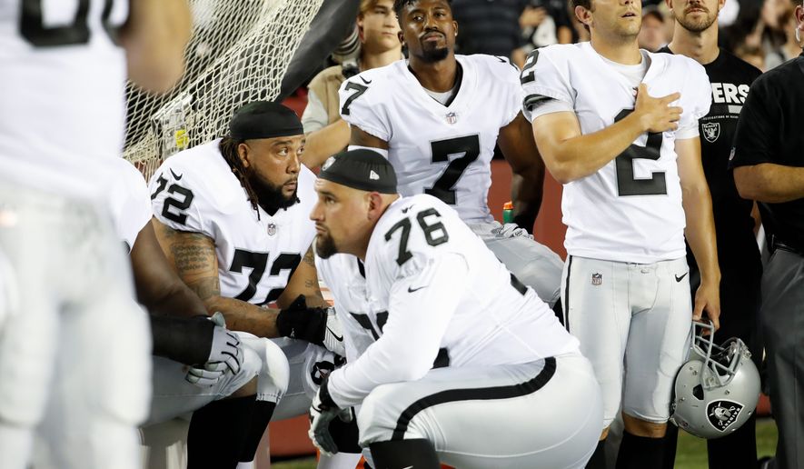 Members of the Oakland Raiders take a knee while others stand during the national anthem. (Associated Press)