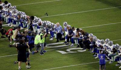The Dallas Cowboys, led by owner Jerry Jones, center, take a knee prior to the national anthem prior to an NFL football game against the Arizona Cardinals.