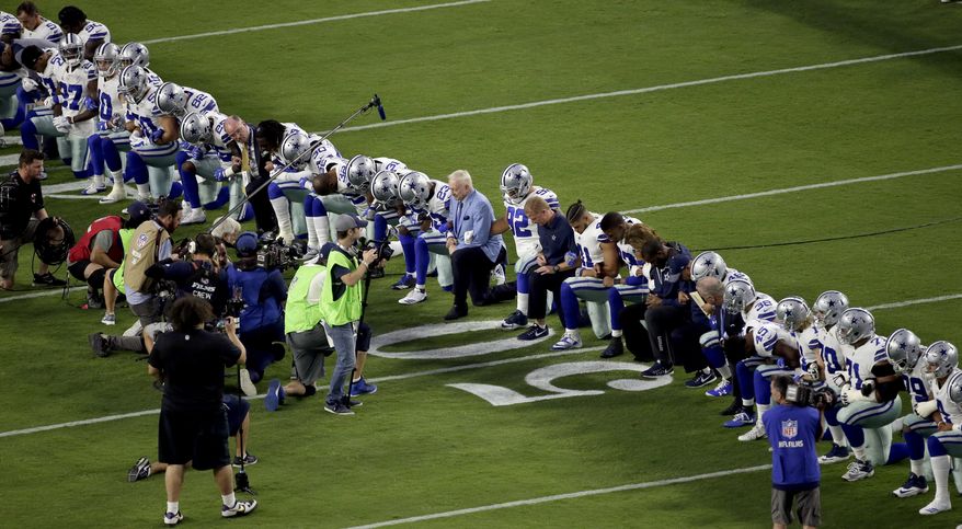 The Dallas Cowboys, led by owner Jerry Jones, center, take a knee prior to the national anthem prior to an NFL football game against the Arizona Cardinals.