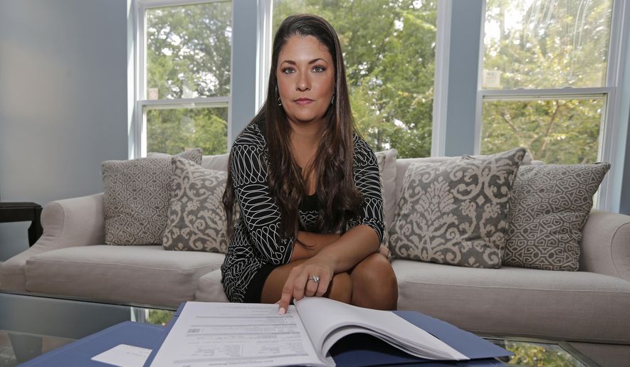 Former Word of Faith Fellowship church member Rachael Bryant poses for a photo with her tax records at her home in Charlotte, N.C., Tuesday, Sept. 19, 2017. She and 10 other members of the evangelical North Carolina-based church say their leader, Jane Whaley, coerced congregants into filing false unemployment claims after the faltering economy threatened weekly tithes from church-affiliated companies. (AP Photo/Chuck Burton)