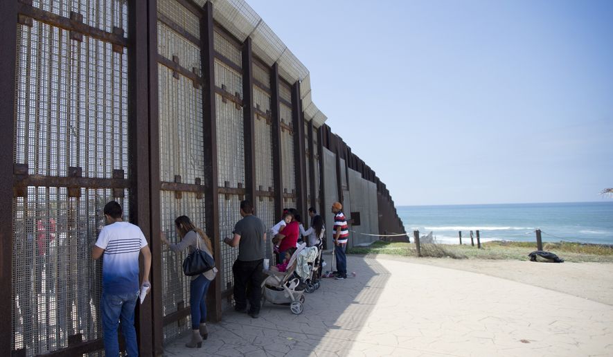 In this May 1, 2016, file picture, Eva Lara, second from let, reacts as she reaches for her grandmother Juana Lara through the border wall during a brief visitation near where Mexico and the United States meet at the Pacific Ocean in San Diego. (AP Photo/Gregory Bull, File)