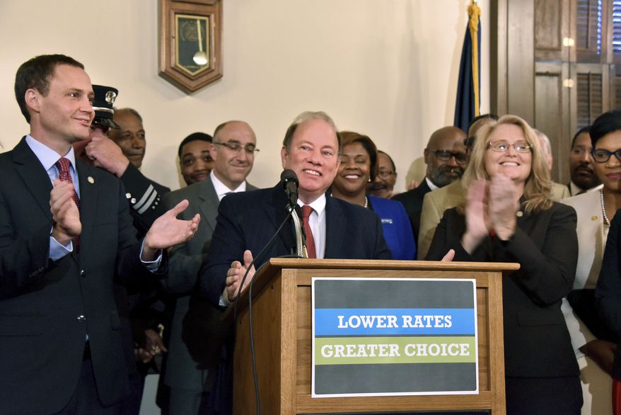 Speaker of the Michigan House Tom Leonard, R-Dewitt, left, Detroit Mayor Mike Duggan, and Rep. Lana Theis, R-Brighton, right, chair of the House Committee on Insurance, announce bi-partisan legislation designed to reduce Michigan drivers' insurance payments Tuesday, Sept. 26, 2017, in Lansing, Mich. (Dale G Young/Detroit News via AP)