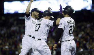 Colorado Rockies shortstop Trevor Story, center, is congratulated by Mark Reynolds, left, and Nolan Arenado as Story returns to the dugout after hitting a three-run home run off Miami Marlins starting pitcher Jose Urena in the first inning of a baseball game Tuesday, Sept. 27, 2017, in Denver. (AP Photo/David Zalubowski)
