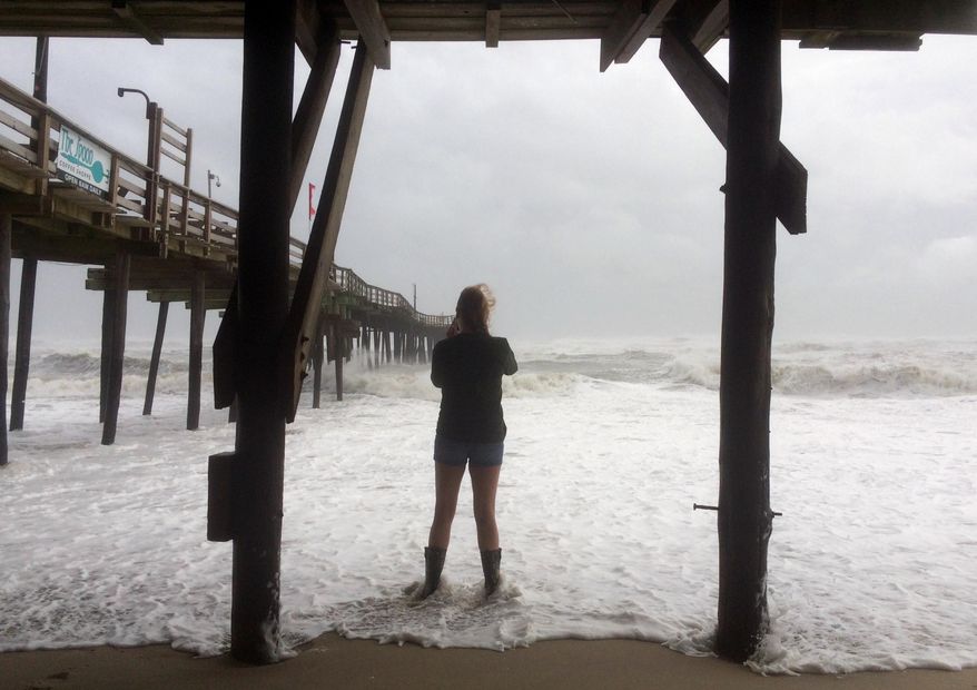 A woman stands in the water as Hurricane Maria moves closer to North Carolina's Outer Banks on Tuesday, Sept. 26, 2017. Thousands of visitors abandoned their vacation plans and left the area as the hurricane moved northward in the Atlantic, churning up surf and possible flooding. (AP Photo/Ben Finley)