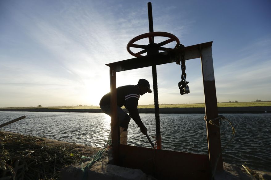 FILE - In this March 26, 2014 file photo, Abelardo Martinez works to clear a blocked duct which leads water to his fields near Colonia Coahuila, Mexico, through a maze of canals from the Colorado River. The U.S. and Mexico have agreed to expand a far-reaching conservation agreement that governs how they manage the overused Colorado River, which supplies water to millions of people and farms in both nations. Officials of U.S. water districts say the agreement to be signed Wednesday, Sept. 27, 2017 calls for the United States to invest $31.5 million to improve Mexico's water infrastructure, with the resulting water savings to be shared by users in both nations and by environmental projects. (AP Photo/Gregory Bull, File)