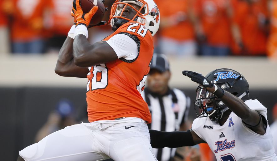 FILE - In this Aug. 31, 2017, file photo, Oklahoma State wide receiver James Washington (28) catches a pass for a touchdown, in front of Tulsa cornerback Kerwin Thomas (2) during the first half of an NCAA college football game in Stillwater, Okla. Oklahoma State faces Texas Tech this week in a matchup of the Big 12's top two passing teams. (AP Photo/Sue Ogrocki, File)