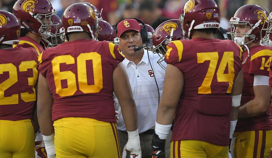 FILE - In this Sept. 16, 2017, file photo, Southern California head coach Clay Helton talks to his team during the first half of an NCAA college football game against Texas in Los Angeles. With a quarter of the college football season in the books, 24 undefeated teams remain, along with the possibility that each Power Five conference could have an undefeated champion. That’s way off. For now, a couple of cross-divisional conference games matching ranked teams, No. 2 Clemson at No. 12 Virginia Tech and No. 5 USC at No. 16 Washington State, highlight the schedule and will be part whittling the field of unbeaten teams. (AP Photo/Mark J. Terrill, File)