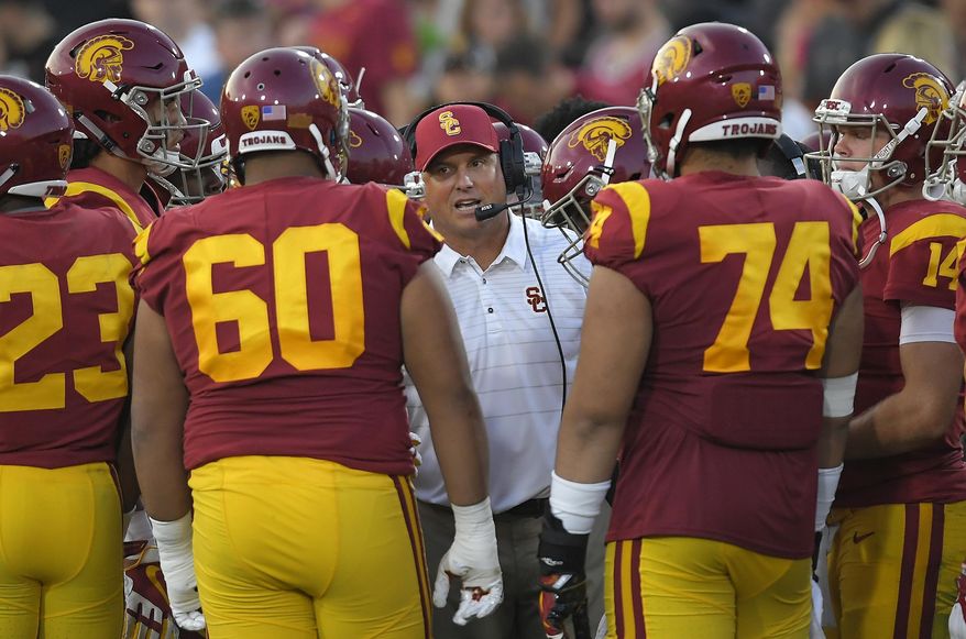 FILE - In this Sept. 16, 2017, file photo, Southern California head coach Clay Helton talks to his team during the first half of an NCAA college football game against Texas in Los Angeles. With a quarter of the college football season in the books, 24 undefeated teams remain, along with the possibility that each Power Five conference could have an undefeated champion. That’s way off. For now, a couple of cross-divisional conference games matching ranked teams, No. 2 Clemson at No. 12 Virginia Tech and No. 5 USC at No. 16 Washington State, highlight the schedule and will be part whittling the field of unbeaten teams. (AP Photo/Mark J. Terrill, File)