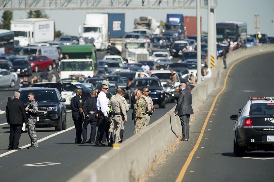 Police officers investigate the scene of a standoff with a suspect driving a sports utility vehicle on westbound Interstate 80 on Wednesday, Sept. 27, 2017, in Emeryville, Calif. The incident, which ended in gunfire, shut freeway traffic in both directions at the height of morning rush hour. (AP Photo/Noah Berger)