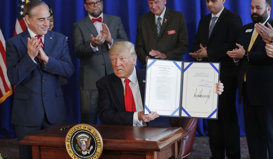 FILE - In this Saturday, Aug. 12, 2017 file photo, President Donald Trump holds the Veteran's Affairs Choice and Quality Employment Act of 2017 after signing it at Trump National Golf Club in Bedminister, N.J. Standing with Trump is Veterans Affairs Secretary David Shulkin, left. Weeks after receiving emergency aid in August 2017, the Department of Veterans Affairs is cautioning that the private-sector health program backed by Trump could run low again on money sooner than expected, threatening to disrupt care for hundreds of thousands of veterans in two months. (AP Photo/Pablo Martinez Monsivais)