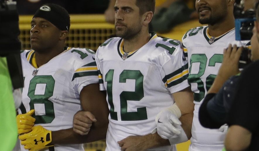 Green Bay Packers' Aaron Rodgers links arms with Richard Rodgers and Randall Cobb during the national anthem before an NFL football game against the Chicago Bears Thursday, Sept. 28, 2017, in Green Bay, Wis. (AP Photo/Morry Gash)