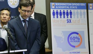 Washington Attorney General Bob Ferguson, second from left, listens to a question, Thursday, Sept. 28, 2017, in Seattle, as he stands near a chart detailing increases in overdoses and hospital stays relating to opioid use in Washington state. Ferguson said Thursday that the state and the city of Seattle are filing lawsuits against several makers of opioids, including Purdue Pharma, seeking to recoup costs incurred by government when the drugs -- which many officials blame for a national addiction crisis -- are abused. (AP Photo/Ted S. Warren)