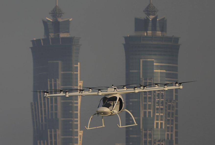 In this Sept. 26, 2017 photo, a Volocopter prototype flies in front of the two hotel towers during a test flight in Dubai, United Arab Emirates. Dubai is hoping to one day have flying, pilotless taxis darting among its skyscrapers. Just this week, the city-state in the United Arab Emirates hosted crews from the German company Volocopter, which had an electric, battery-powered two-seat prototype take off and land. Dubai hopes to have rules in place in the next five years to be ready for having the aircraft regularly flying through its skies. (AP Photo/Kamran Jebreili)